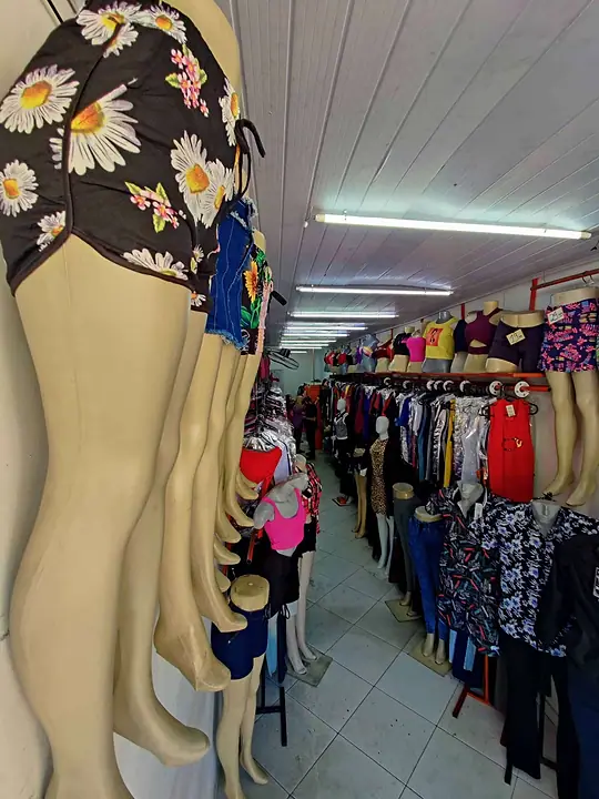 Corredor da loja com araras de roupas e manequins de calça